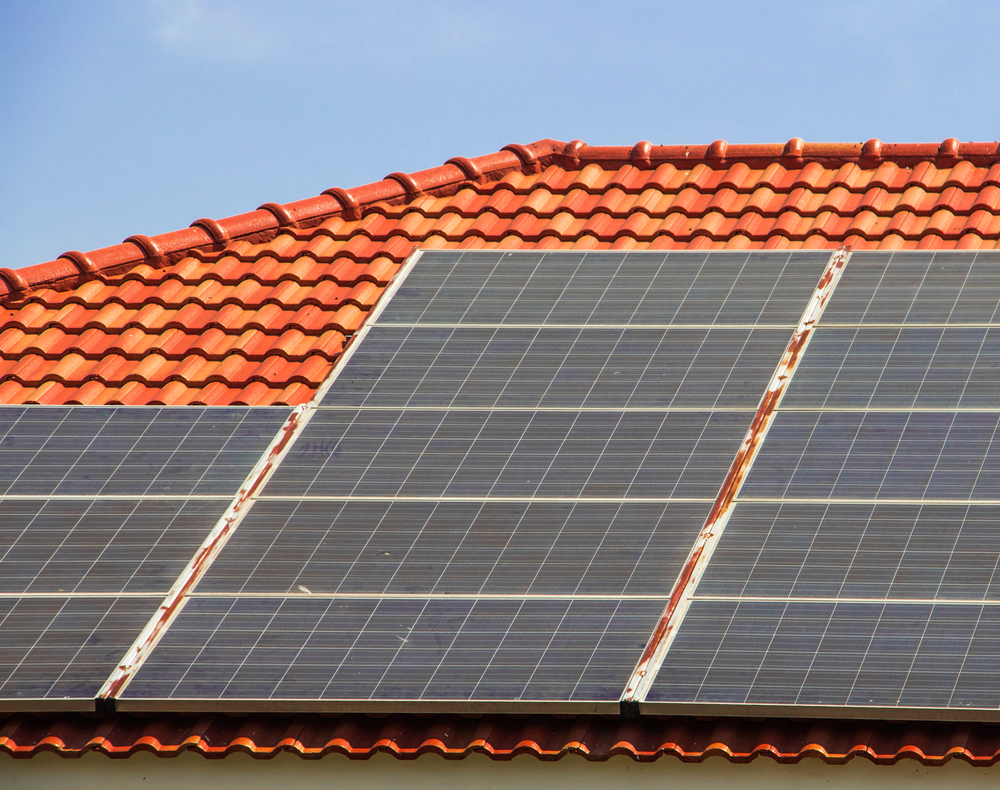 Image of a red tiled roof with solar panels.
