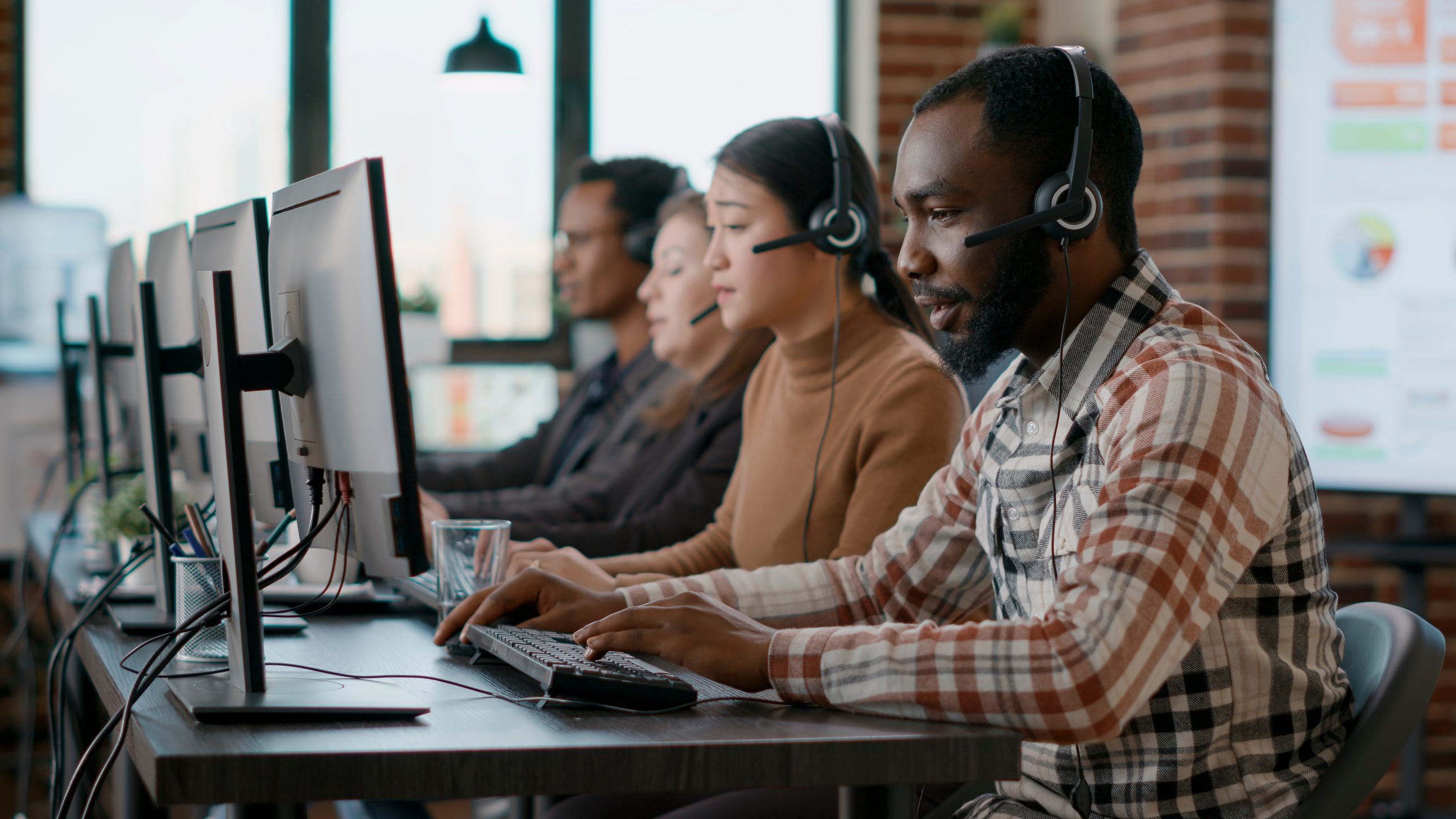 Group of people working at computers, possibly in a call centre.