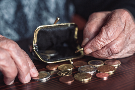 Photograph of two hands of an older person going through a purse and counting pennies.