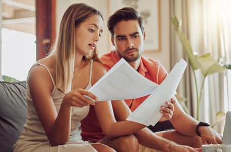 Young couple (a woman and a man) looking at bills (sheets of paper)