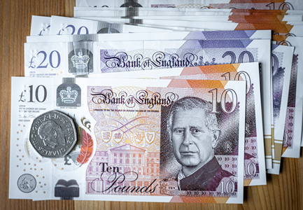Photograph of UK pound notes and a 50 pence coin.