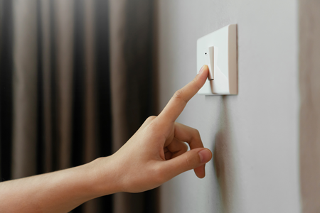 Photo of a hand switching on a light switch