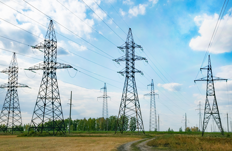 Electricity pylons under a blue sky with a few clouds.