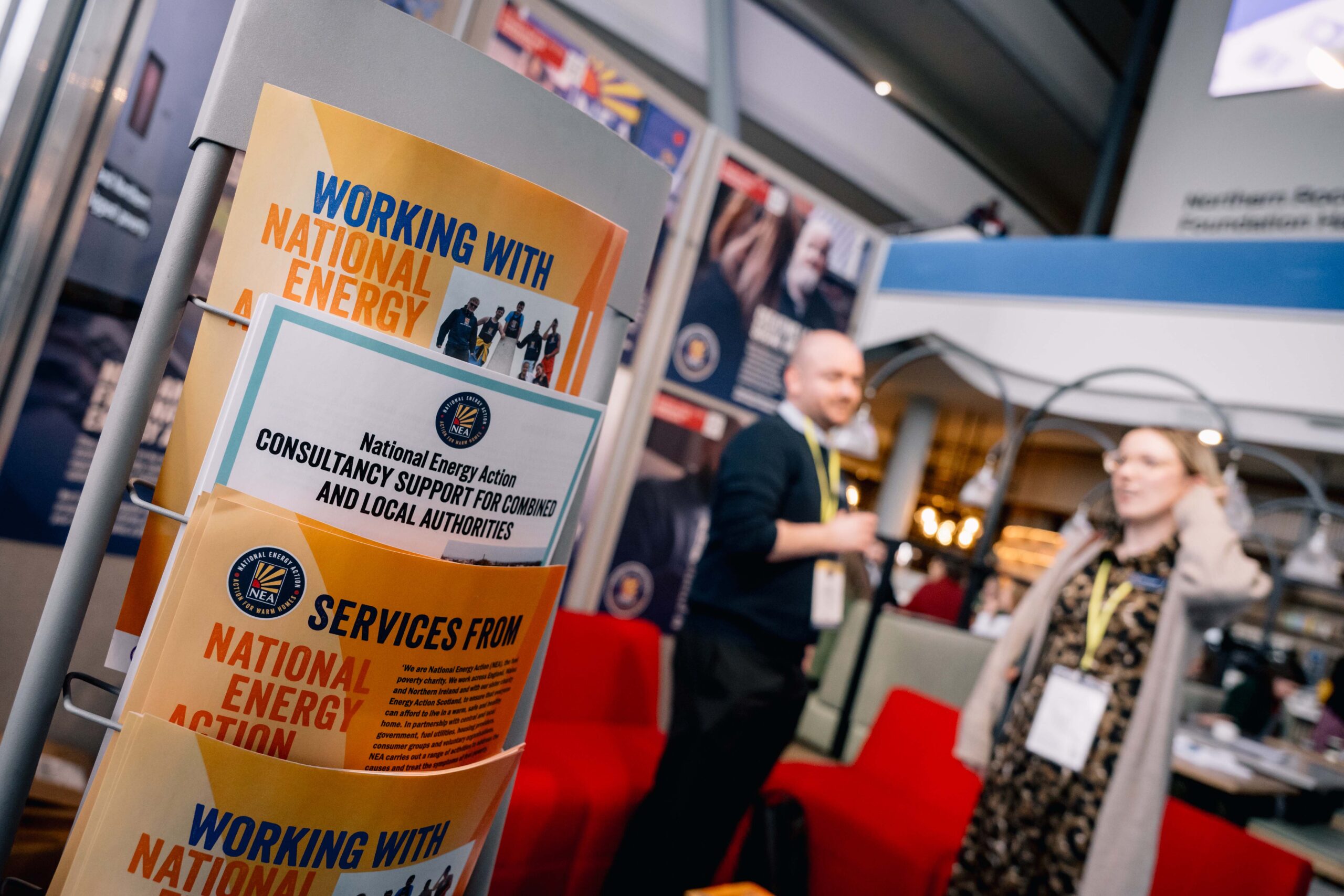 An image showing leaflets on a literature stand and two people in soft focus standing to the right