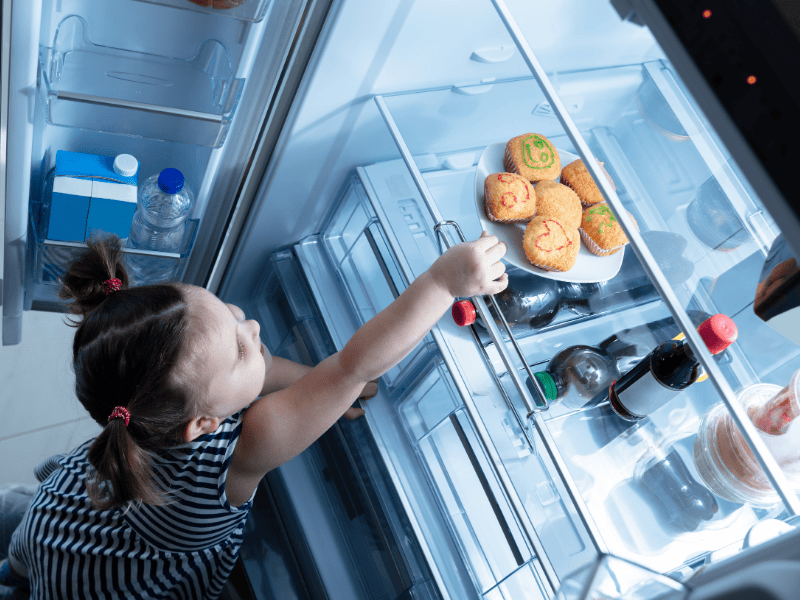 Child reaching for food in fridge