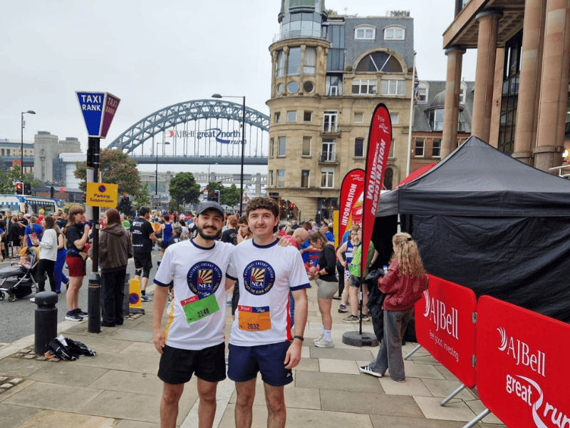 Two runners with Team NEA t shirts by Newcastle Tyne bridge