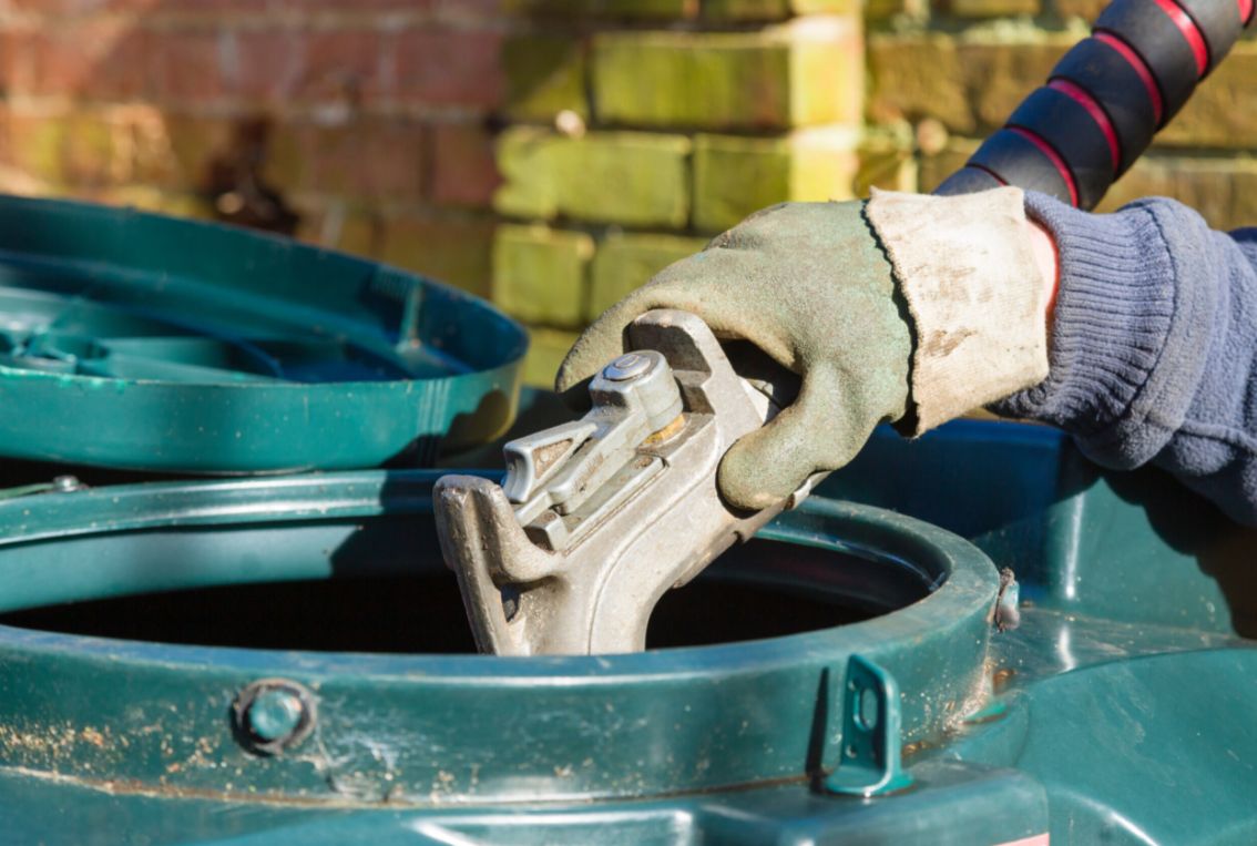 A photo of a gloved hand putting home heating oil into a container.