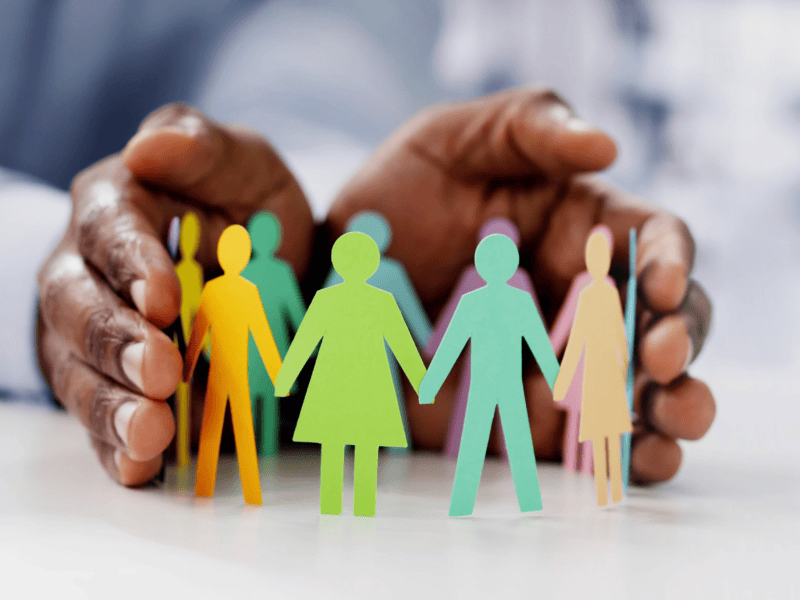 Hands holding paper dolls showing DEI